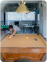 A member of the team leaning over a pool table, ready to make their shot.